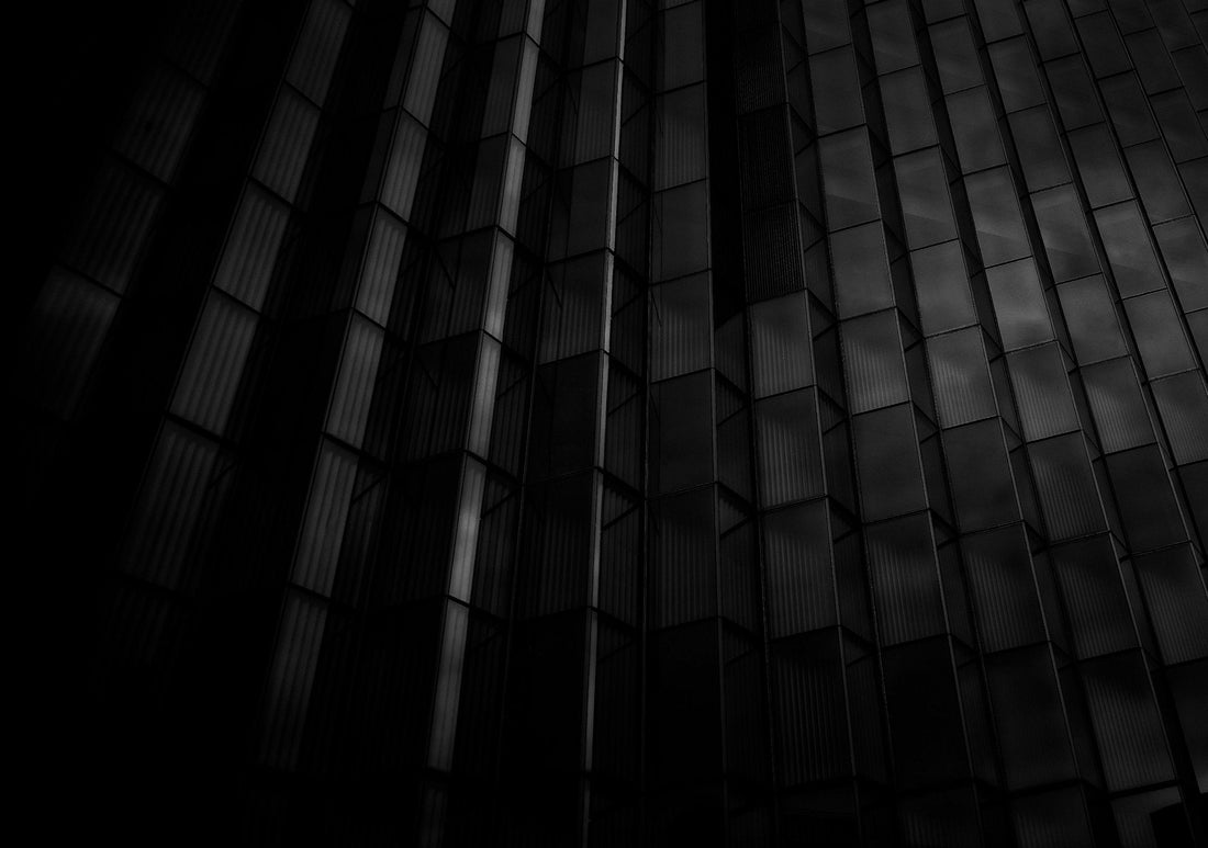 Dark glass building facade with black tones highlighting geometric patterns and reflections